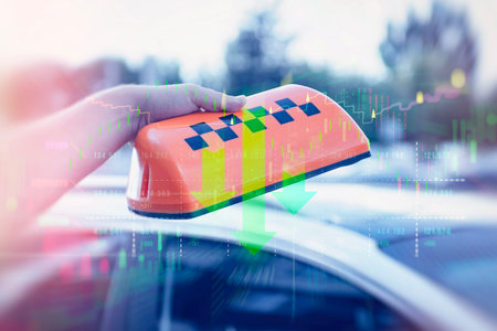 Taxi sign on the roof is held by a man. Digital overlay of financial market graphs and downward arrow. Concept of declining services, cost of travel and market crisis in the transportation industryの写真素材