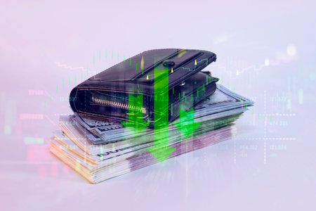 Black wallet on a stack of dollar bills overlaid with green declining financial bar charts and market data. The concept of declining financialsの写真素材