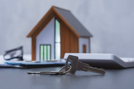 House keys and a stack of dollars with coins and a model house with a calculator. Concept expenses...