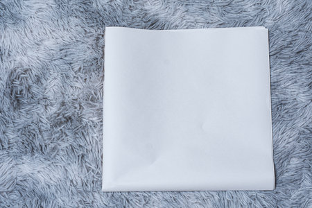 Minimalistic newspaper mockup with blank folded paper lying on a fluffy gray carpet. Layout for showcasing print layout and editorial designの写真素材