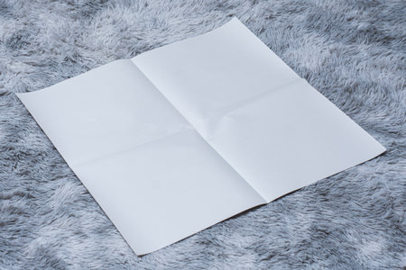 Minimalistic newspaper mockup with blank folded paper lying on a fluffy gray carpet. Layout for showcasing print layout and editorial designの写真素材