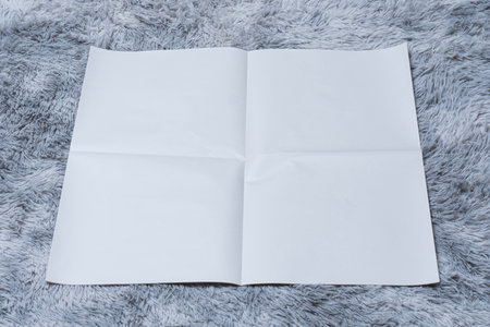 Minimalistic newspaper mockup with blank folded paper lying on a fluffy gray carpet. Layout for showcasing print layout and editorial designの写真素材