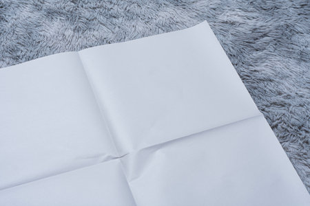 Minimalistic newspaper mockup with blank folded paper lying on a fluffy gray carpet. Layout for showcasing print layout and editorial designの写真素材