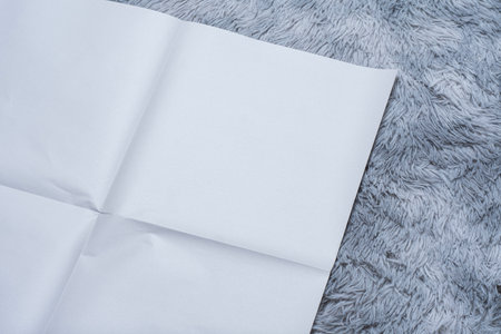 Minimalistic newspaper mockup with blank folded paper lying on a fluffy gray carpet. Layout for showcasing print layout and editorial designの写真素材