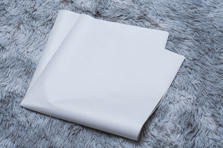 Minimalistic newspaper mockup with blank folded paper lying on a fluffy gray carpet. Layout for showcasing print layout and editorial designの写真素材