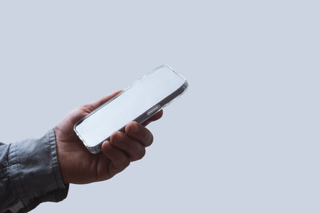 Man in shirt holding smartphone with blank screen on light background. Portable mobile technology conceptの写真素材
