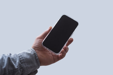 Man in shirt holding smartphone with blank screen on light background. Portable mobile technology conceptの写真素材