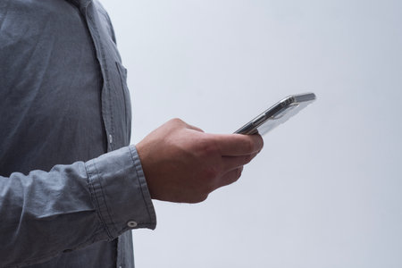 Man in shirt holding smartphone on light background. Portable mobile technology conceptの写真素材