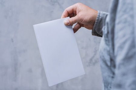 Realistic mockup of book cover, magazine in the hands of a man on concrete background. Concept for demonstrating editorial design, book covers and printed materialsの写真素材