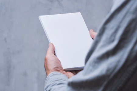 Realistic mockup of book cover, magazine in the hands of a man on concrete background. Concept for demonstrating editorial design, book covers and printed materialsの写真素材