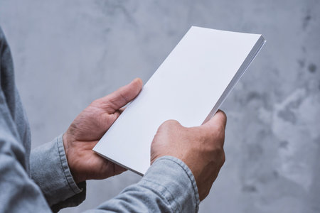 Realistic mockup of book cover, magazine in the hands of a man on concrete background. Concept for demonstrating editorial design, book covers and printed materialsの写真素材