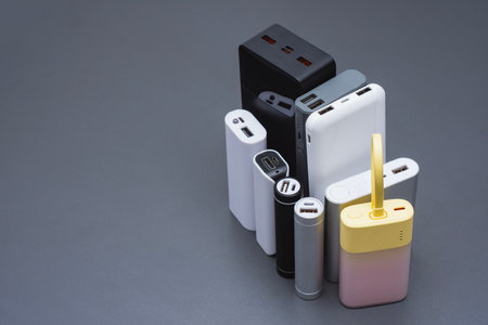 A group of power banks in various shapes, sizes, and colors on a table. Concept portable charging solutions, mobile technology, and on-the-go energy backup for smartphones and devicesの写真素材