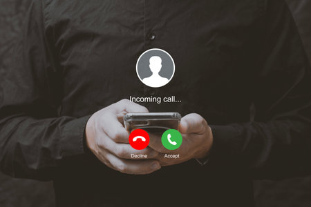 Man holding smartphone with incoming call interface screen. Close-up of hands holding mobile phone with call accept and decline buttons on displayの写真素材