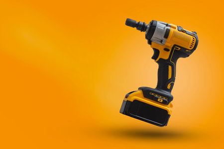 Cordless impact wrench on yellow background with dynamic light. Electric tool for construction, car...