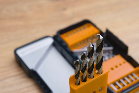 Close-up of a metal drill bit set organized in plastic case on wooden table. Concept of tools,...