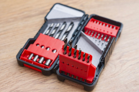 Close-up of a metal drill bit set organized in plastic case on wooden table. Concept of tools,...