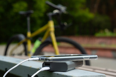 Smartphone in clear case connected to white power bank. Concept mobile device charging setup for cycling and outdoor activitiesの写真素材