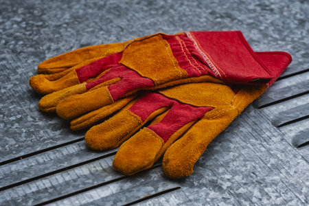 Pair of protective leather and fabric work gloves on a galvanized metal background. Industrial...