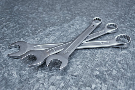 Close-up of shiny chrome wrenches arranged on a galvanized steel surface. Concept precision,...