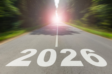 Straight road leading into bright sunlight with large 2026 numbers painted on asphalt. Concept of new year journey, success, and future opportunities.の写真素材