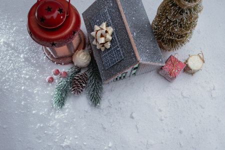 Miniature Christmas house with solar panels on the roof, glowing red lantern and snowy festive decorations. Cozy winter holiday scene for seasonal designs, New Year and Christmasの写真素材