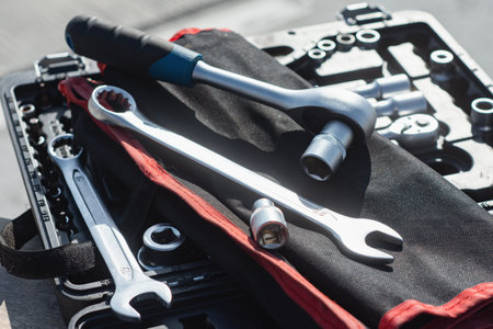 Assorted socket wrenches and ratchet wrench with rubber grip handle neatly arranged in a red fabric...