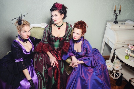 Three young dames in gorgeous historical dresses looking intensely at the viewerの写真素材