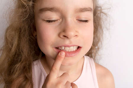 Attractive little girl stands on a white background with empty copy space, happy expression on her face with a beautiful smile, children crooked teeth, pediatric dentistryの写真素材