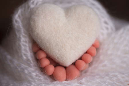 legs and toes of a newborn in a soft white blanket with a heartの写真素材