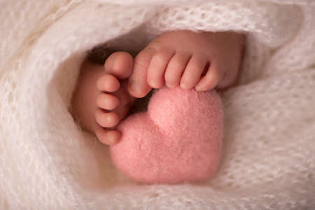 legs and toes of a newborn in a soft white blanket with a pink heartの写真素材