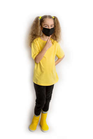 Child in a yellow shirt in a black mask from covid on a white backgroundの写真素材