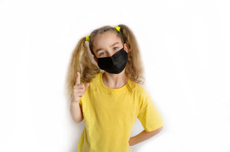 Child in a yellow shirt in a black mask from covid on a white backgroundの写真素材