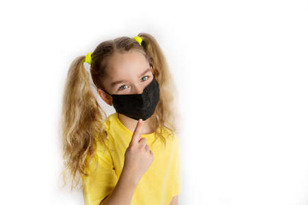 Child in a yellow shirt in a black mask from covid on a white backgroundの写真素材