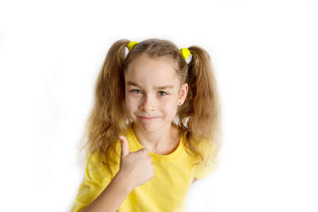 Little blonde girl in a yellow t-shirt makes gestures, raising her fingers, isolated on a white background. Childhood lifestyle conceptの写真素材