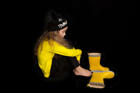 Portrait of pretty cheerful girl, in black and yellow clothes, isolated on black background. Childrens emotionsの写真素材