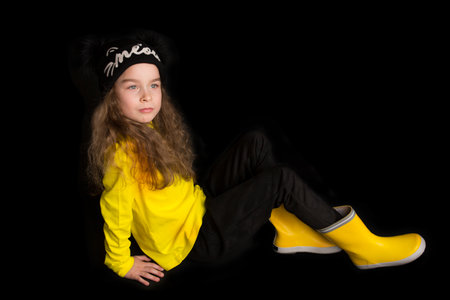 Portrait of pretty cheerful girl, in black and yellow clothes, isolated on black background. Childrens emotionsの写真素材