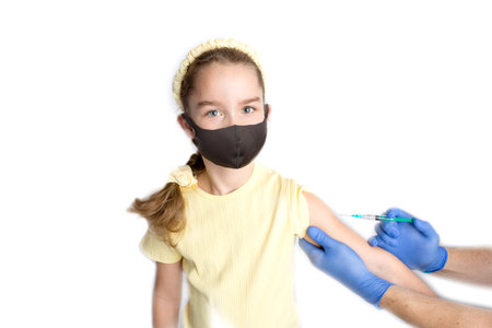 A nurse is giving vaccinations to patients with a syringe. A doctor vaccinates a teenage girl in a hospital. Studio photography on a white background. Close-up shot of injection against covid19.の写真素材