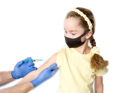 A nurse is giving vaccinations to patients with a syringe. A doctor vaccinates a teenage girl in a hospital. Studio photography on a white background. Close-up shot of injection against covid19.の写真素材