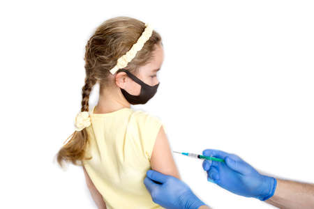 A nurse is giving vaccinations to patients with a syringe. A doctor vaccinates a teenage girl in a hospital. Studio photography on a white background. Close-up shot of injection against covid19.の写真素材