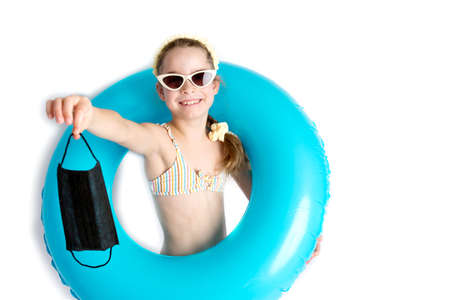Happy little girl takes off protective medical black mask from face outdoors. Victory over...