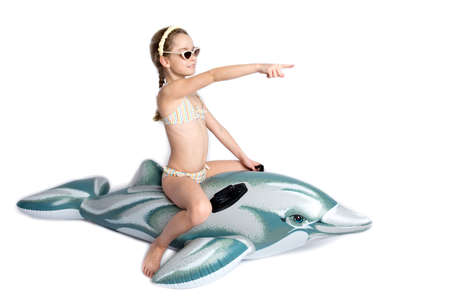 Happy child in a in a bathing suit on an inflatable dolphin. Coronavirus pandemic and healthy lifestyle concept.の写真素材