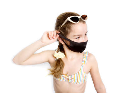 Happy little girl takes off protective medical black mask from face outdoors.の写真素材