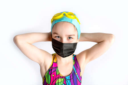 Happy little girl takes off protective medical black mask from face outdoors.の写真素材