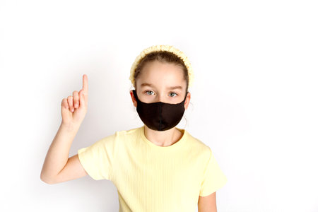 A schoolgirl in a black protective mask draws attention to the correctness and compulsory wearing of protective masks.の写真素材