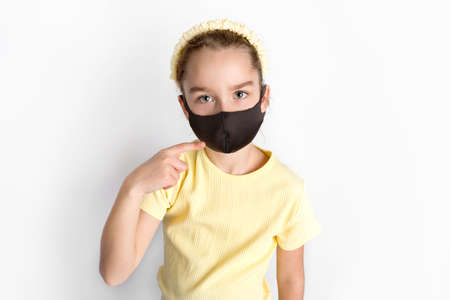 A schoolgirl in a black protective mask draws attention to the correctness and compulsory wearing of protective masks.の写真素材