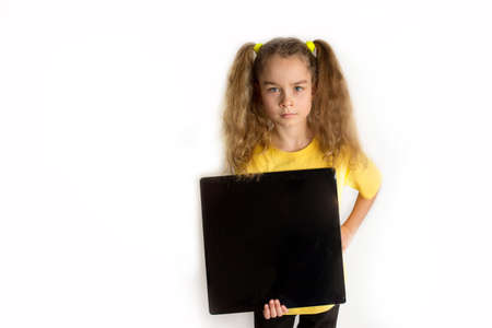 A girl in a yellow T-shot holds a black square for an inscription. White background. Studio photography.の写真素材