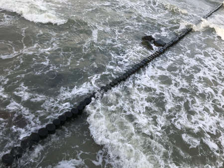 Breaking waves on a wooden breakwater on the Baltic Sea coast.の写真素材