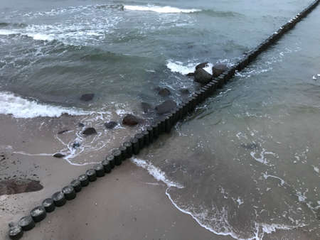 Breaking waves on a wooden breakwater on the Baltic Sea coast.の写真素材
