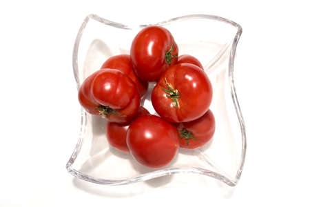 Ripe red tomatoes in a glass vase. White studio background.の写真素材