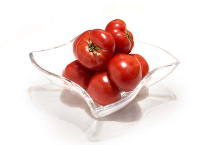 Ripe red tomatoes in a glass vase. White studio background.の写真素材